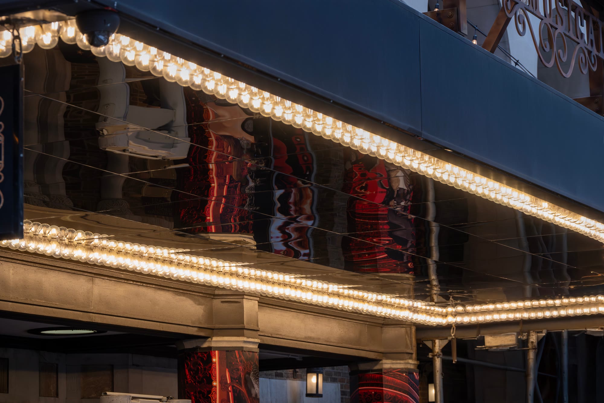 Glowing marquee bulbs above a Broadway theater entrance in New York