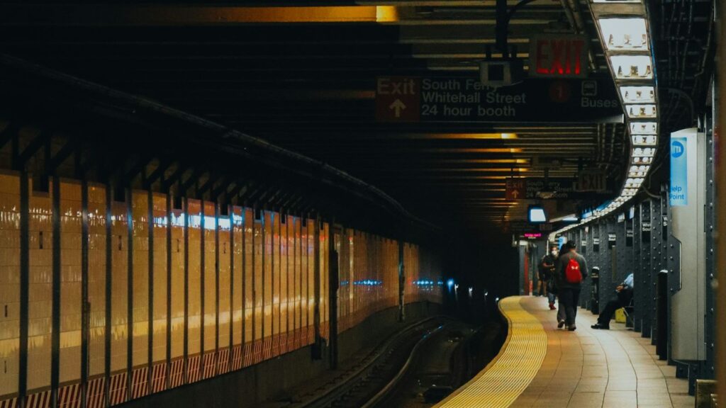 A New York City subway station with a train pulling into the platform