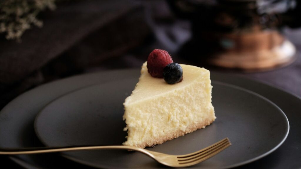 A rich slice of New York cheesecake on a white plate, representing the city's iconic dessert tradition