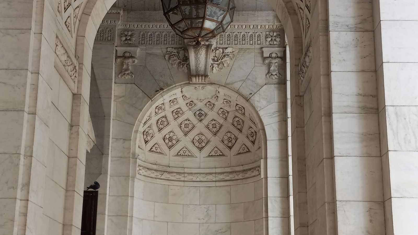 The ornate marble arch and hanging lantern at the entrance of the New York Public Library main branch