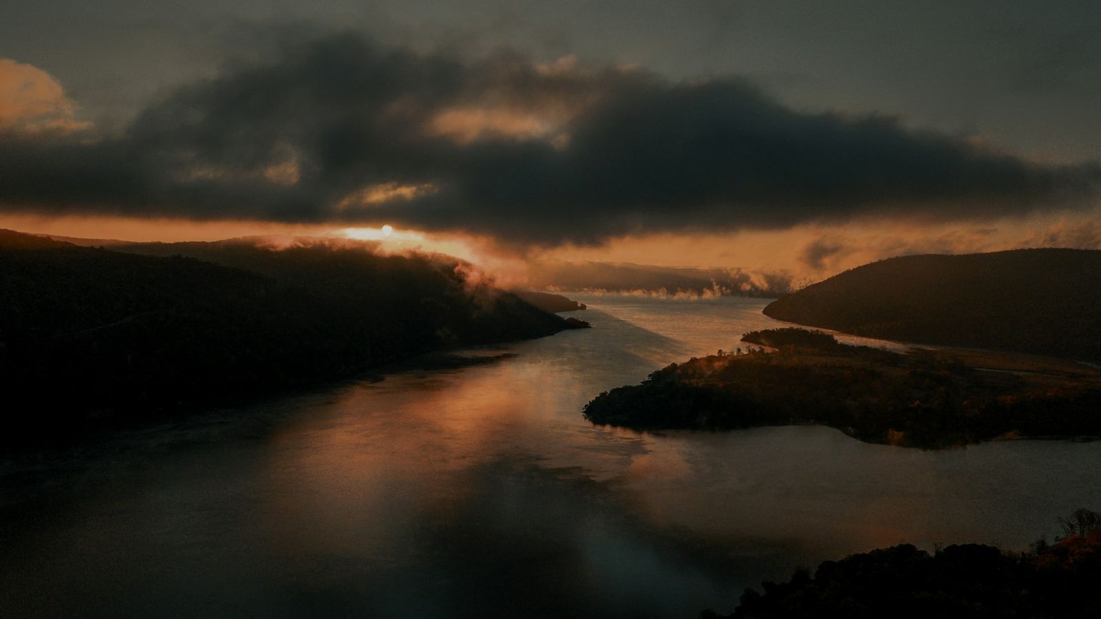 A New York waterway at dawn, with a wooded island rising from the misty waters