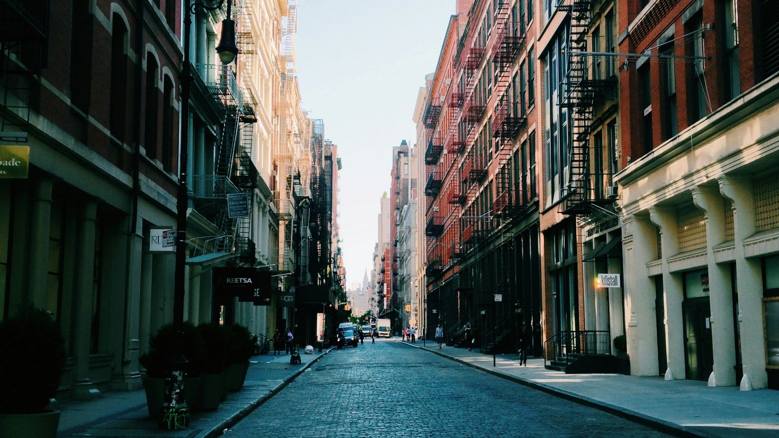 A cobblestone street lined with red brick buildings and fire escapes in Lower Manhattan, New York City