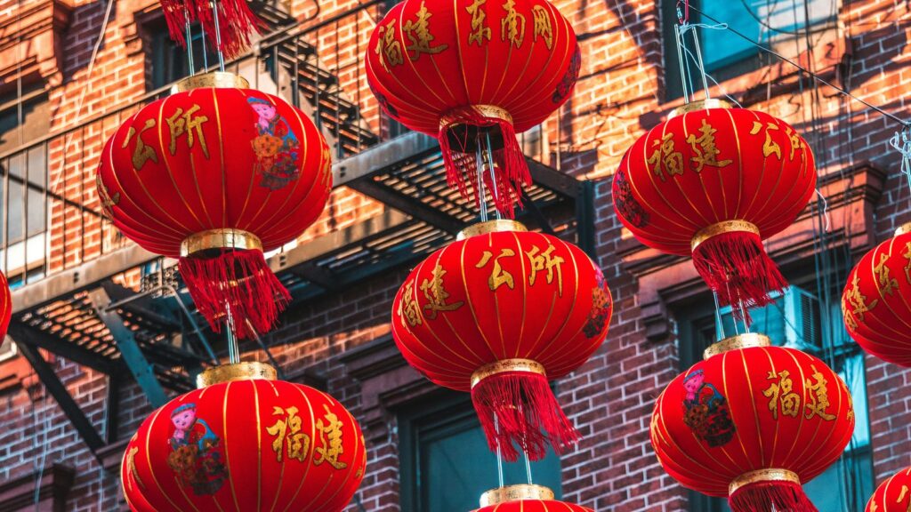 Red Chinese lanterns hanging above the streets of Chinatown in New York City with classic brick tenement buildings