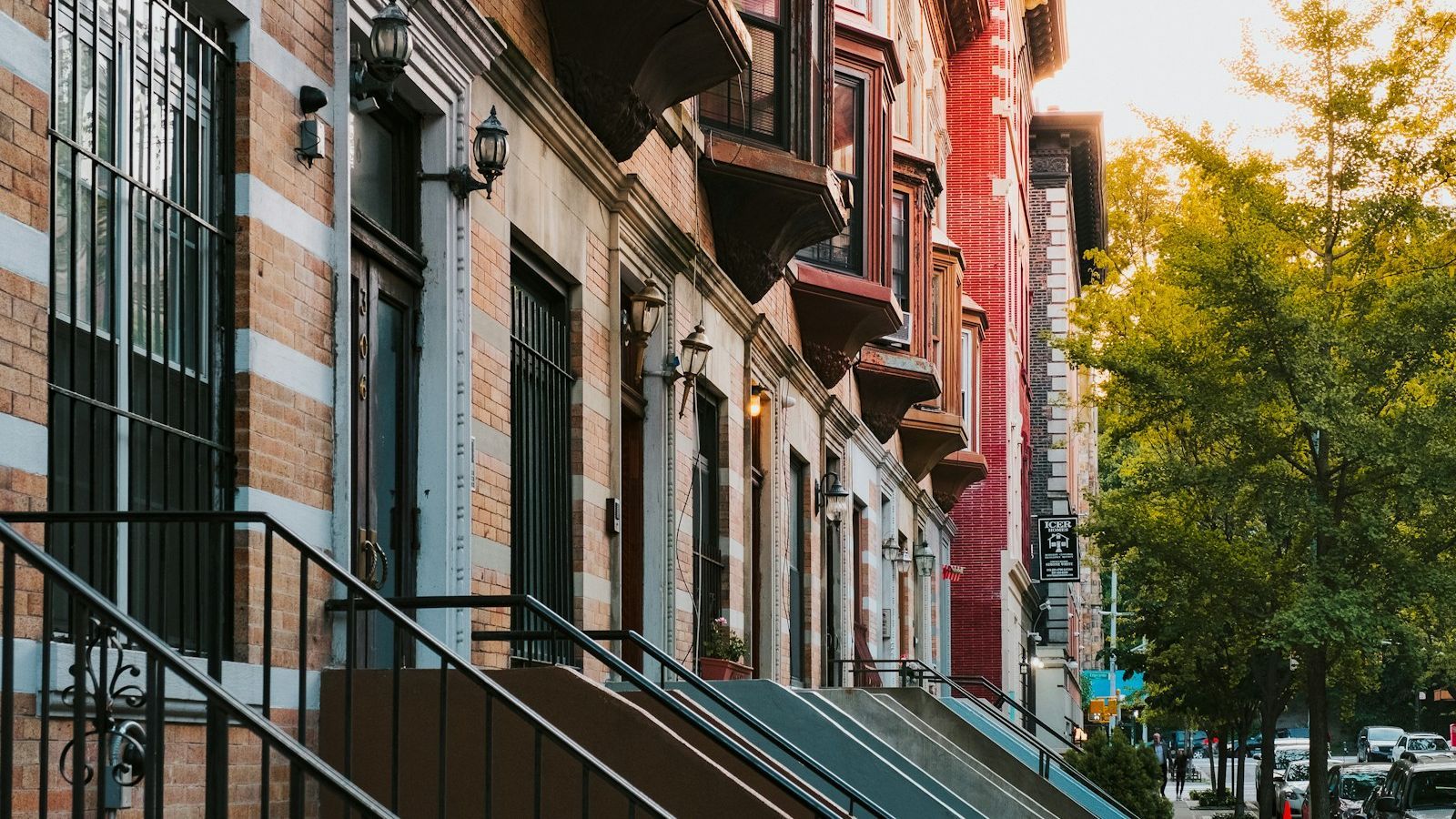 Row of New York City brownstone buildings with iron railings and stoops at golden hour