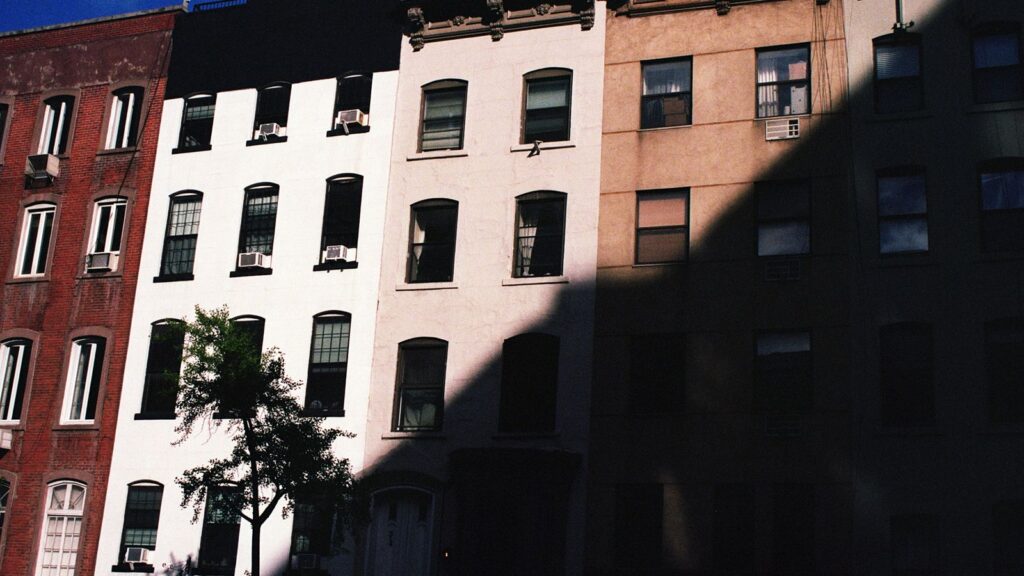 Colorful New York City apartment buildings with fire escapes on a classic NYC neighborhood street