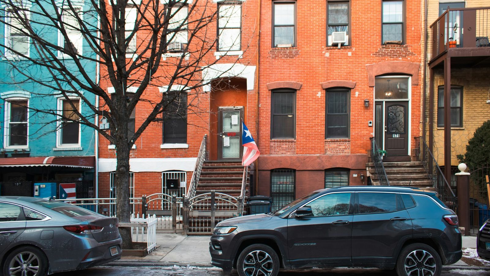 Classic red brick buildings on a Williamsburg Brooklyn street with a parked car