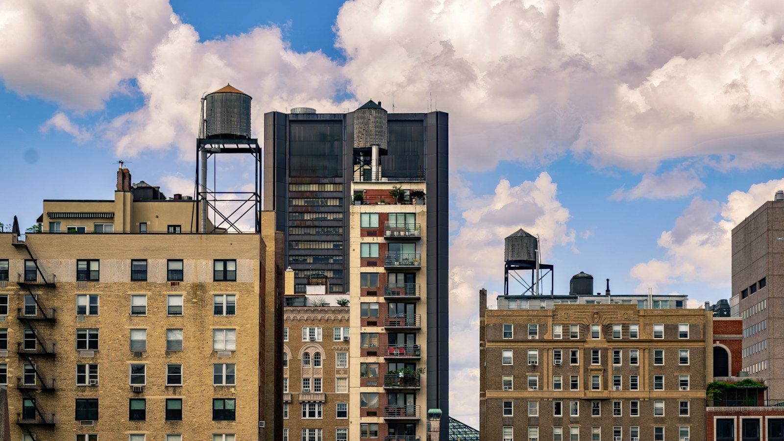 Wooden water towers on the rooftops of Manhattan's upper east side against a blue summer sky