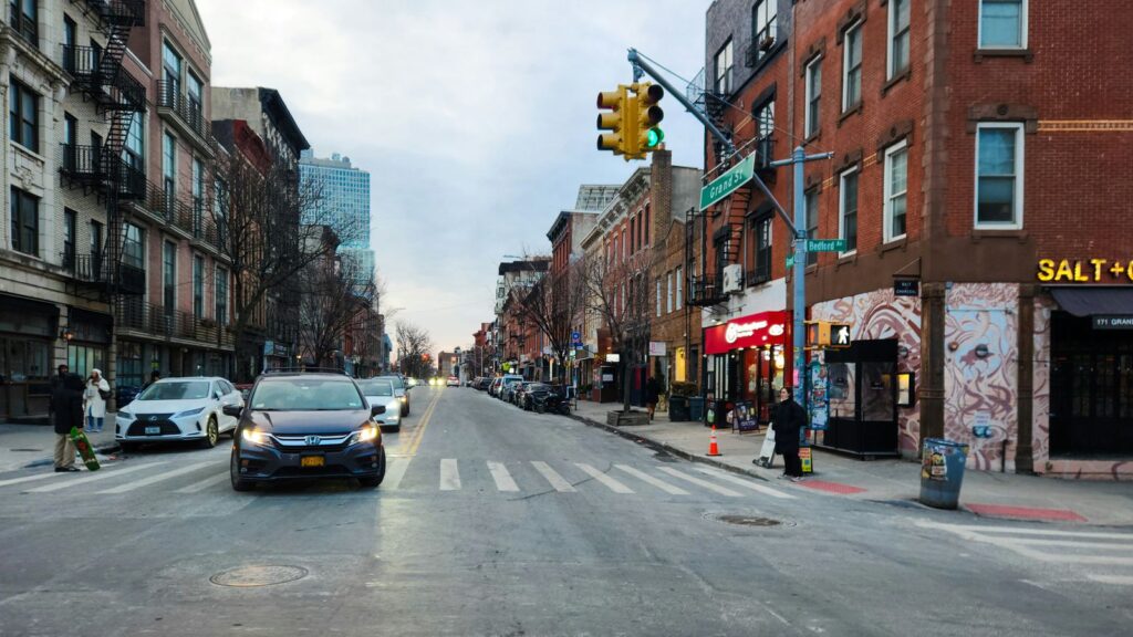 A busy street in Williamsburg, Brooklyn, lined with brownstone buildings, cafes, and local shops