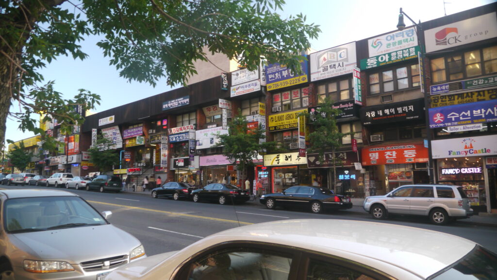 Korean-language shop signs above storefronts on a street in Flushing's Koreatown, Queens