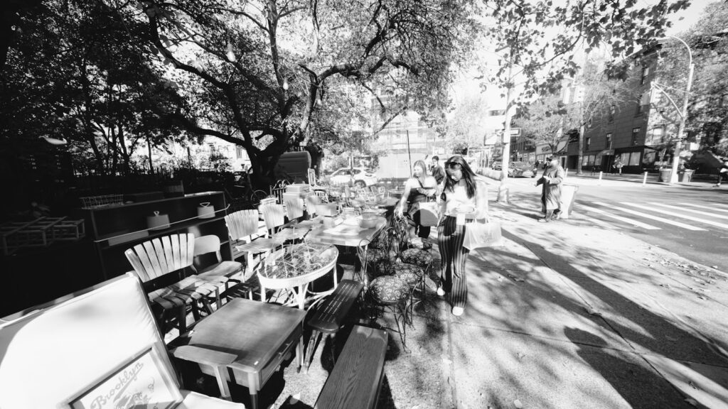 People browsing outdoor market stalls with vintage furniture and goods at the Brooklyn Flea in New York City