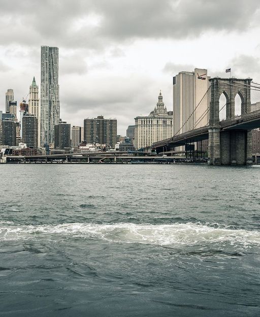 New York City skyline featuring the Brooklyn Bridge and Manhattan buildings viewed from the East River
