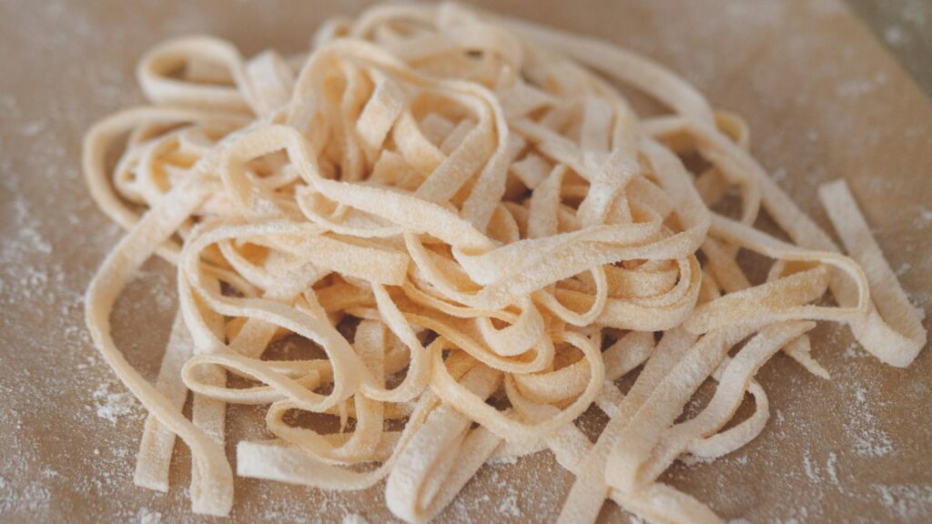 Fresh homemade pasta on a flour-dusted wooden surface, representing the Italian culinary tradition of Arthur Avenue in the Bronx