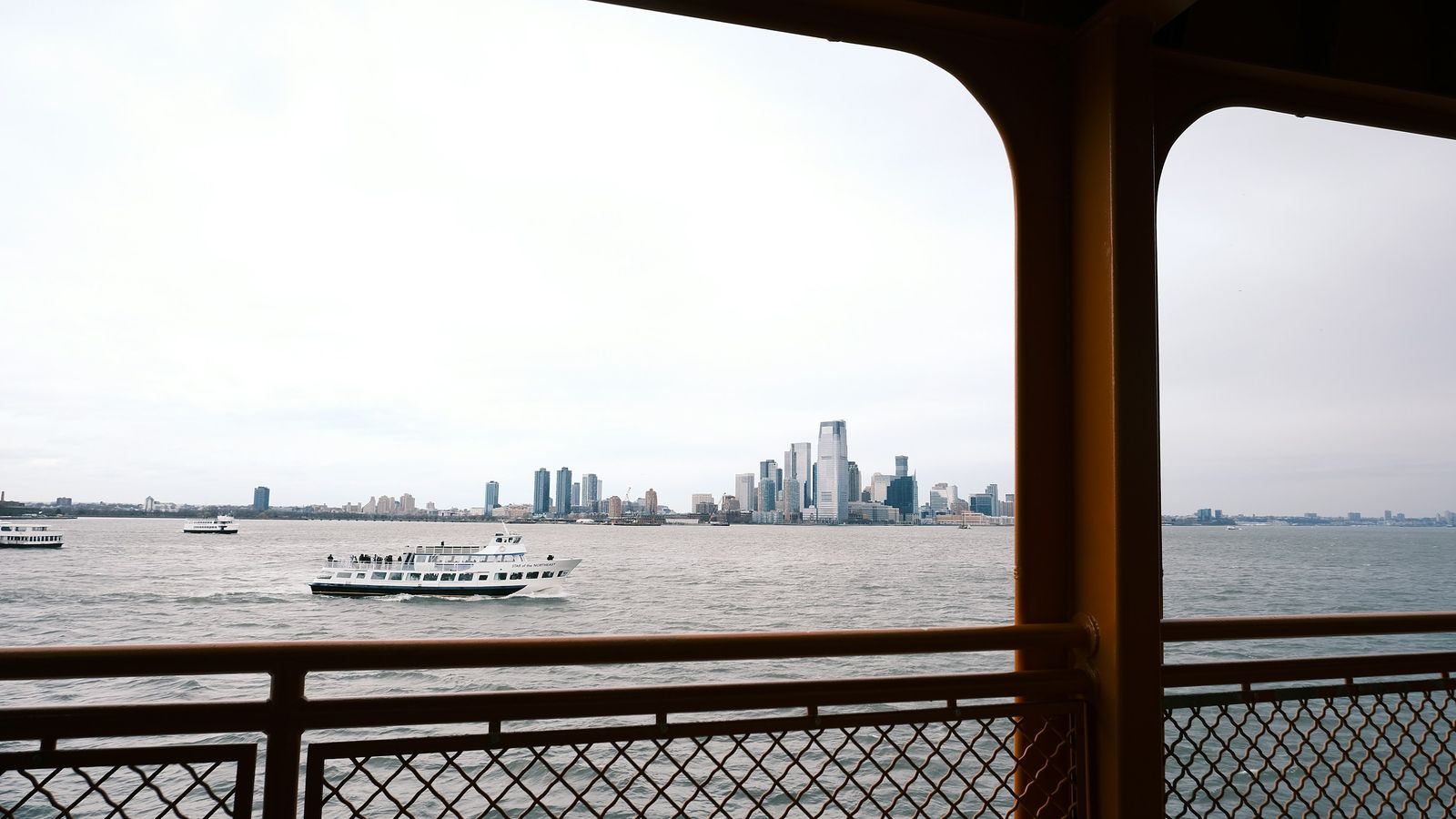 Manhattan skyline viewed from the water with a ferry crossing New York Harbor