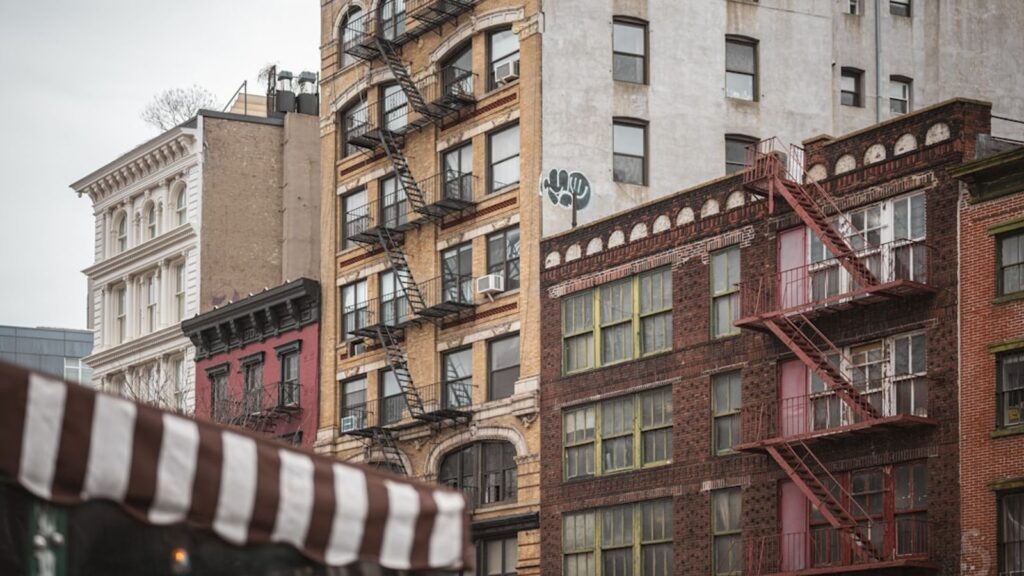 Classic Manhattan tenement buildings with iron fire escapes — the architectural soul of Hell's Kitchen