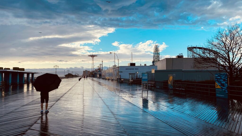 Coney Island boardwalk on a moody day with the Wonder Wheel and Cyclone roller coaster in the distance