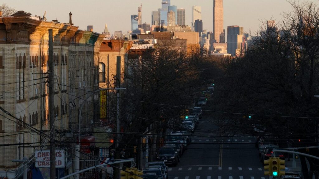Brooklyn street view at sunset with Manhattan skyscrapers visible in the background