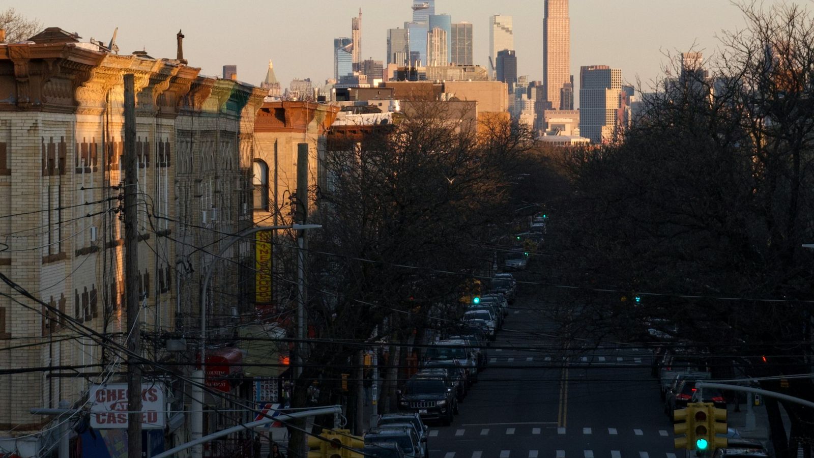 Brooklyn street view at sunset with Manhattan skyscrapers visible in the background