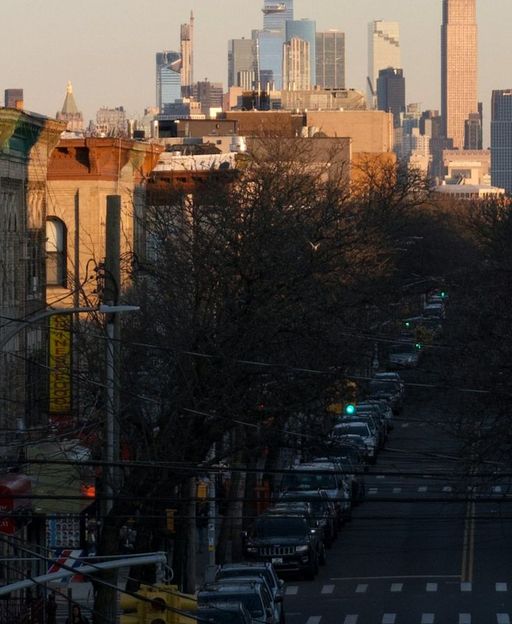 Brooklyn street view at sunset with Manhattan skyscrapers visible in the background