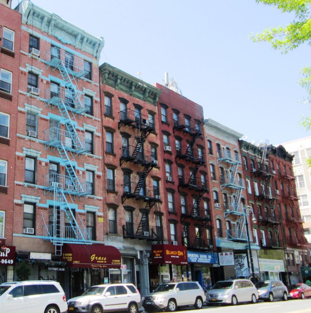 Brick tenement buildings with fire escapes on Essex Street between Hester and Grand Streets, near The Pickle Guys