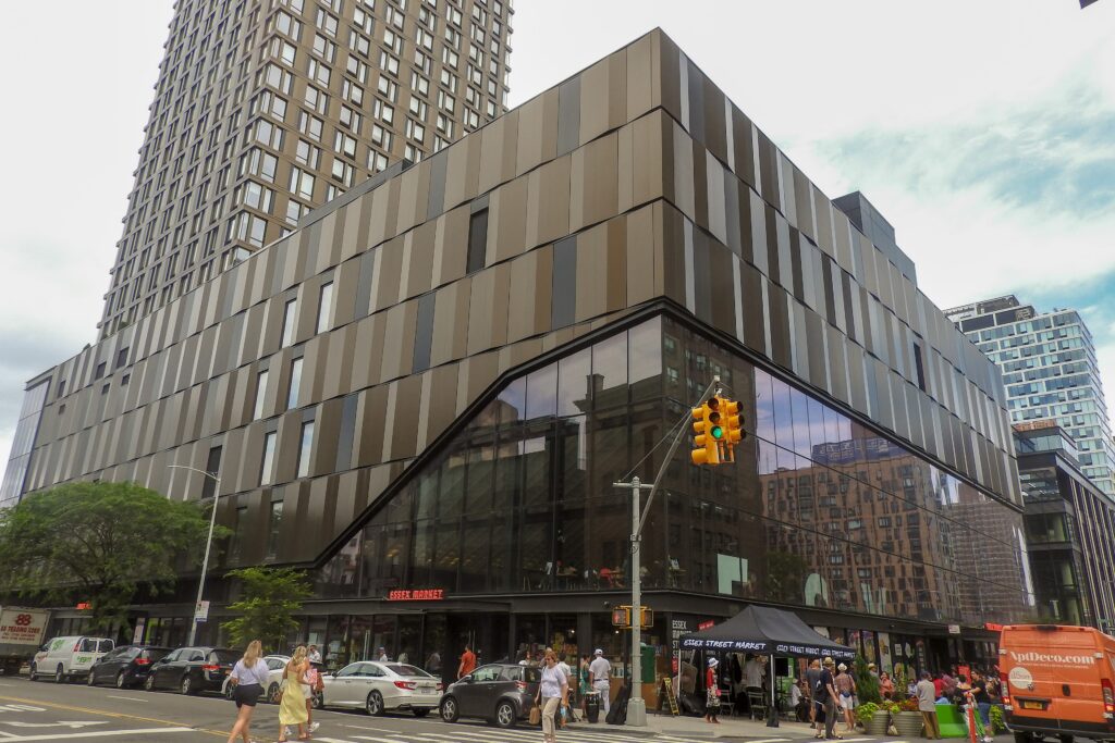 The glass-fronted Essex Market building on the corner of Delancey and Essex Streets, with a market tent outside