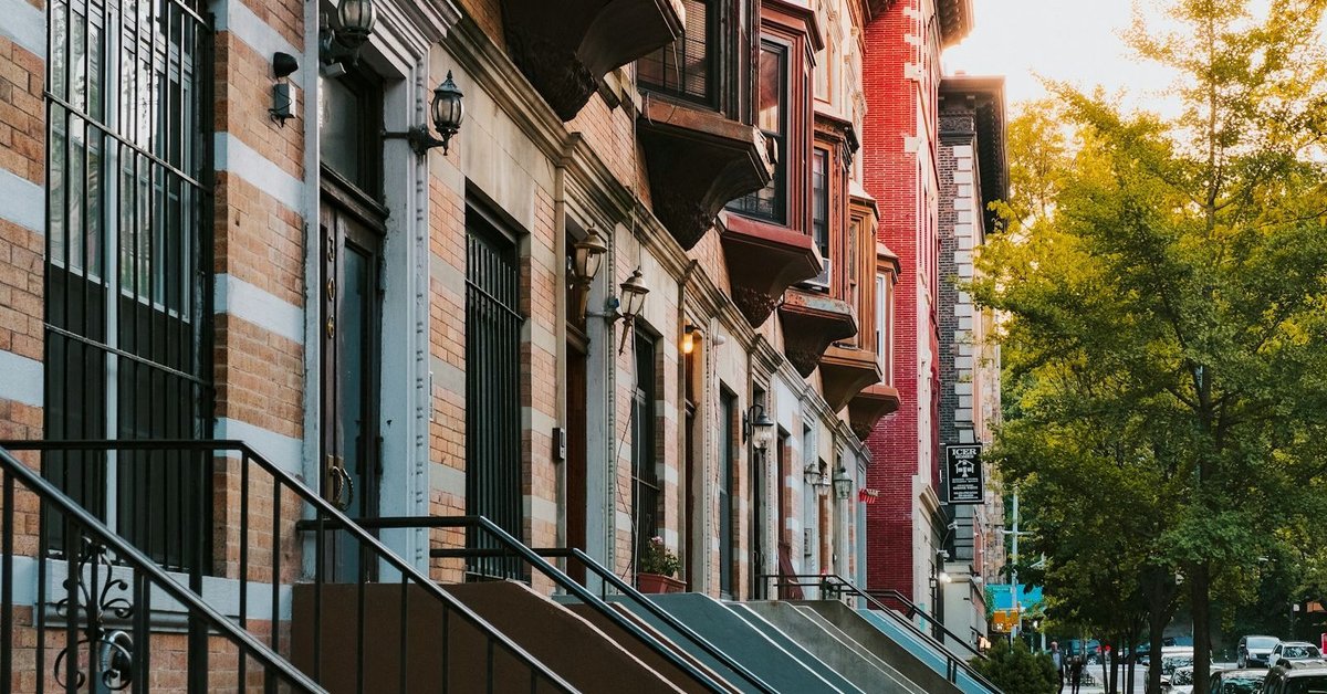 Harlem brownstone row houses with iron stoops and warm golden light — East Harlem, New York City