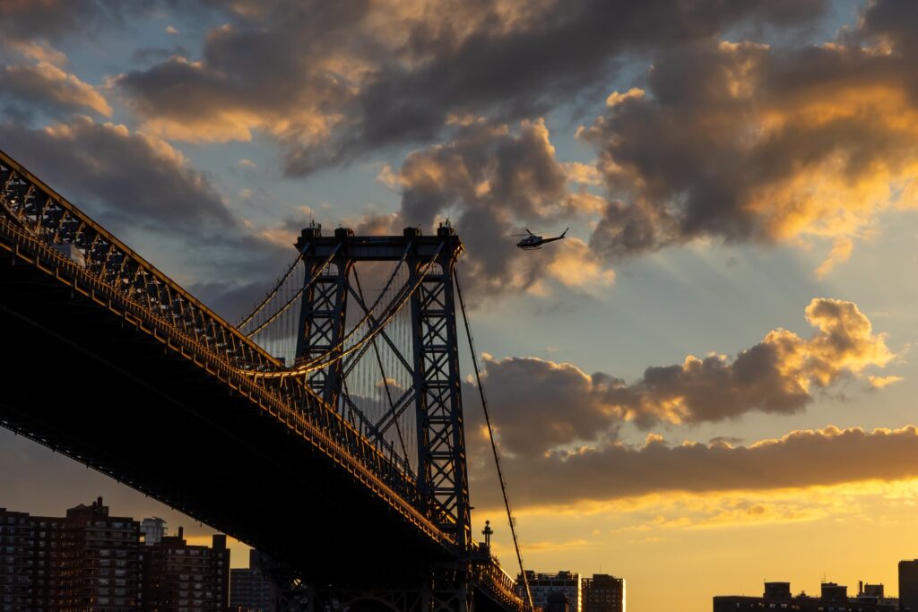The steel towers of the Williamsburg Bridge against a golden sunset sky
