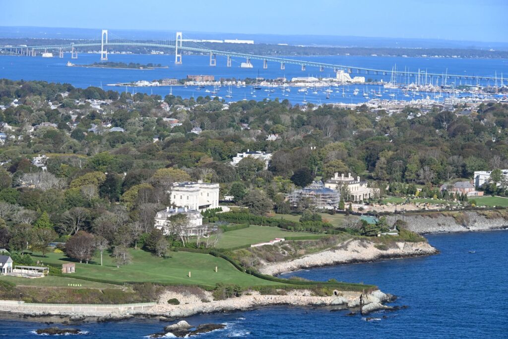 Aerial view of Newport mansions on the rocky shore, with the harbor and the Newport Bridge behind