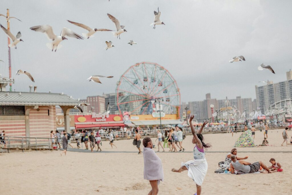 Children playing on the beach at Coney Island, with the Wonder Wheel and the boardwalk behind them