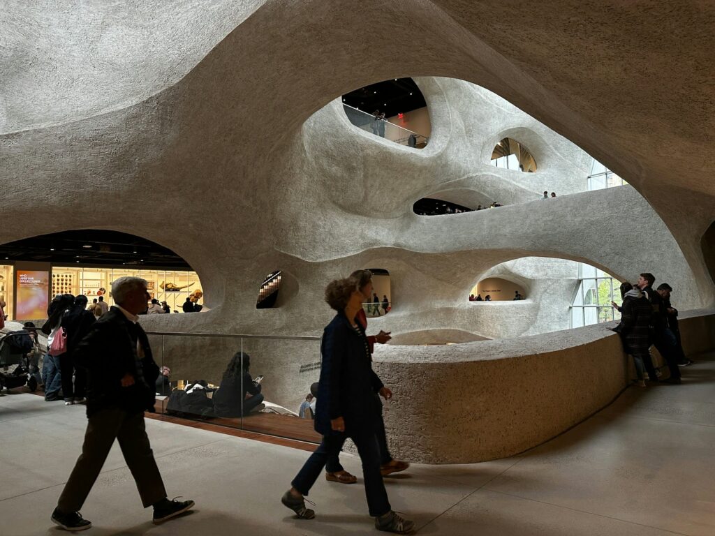 Visitors walking through the curving atrium of the Richard Gilder Center at the American Museum of Natural History