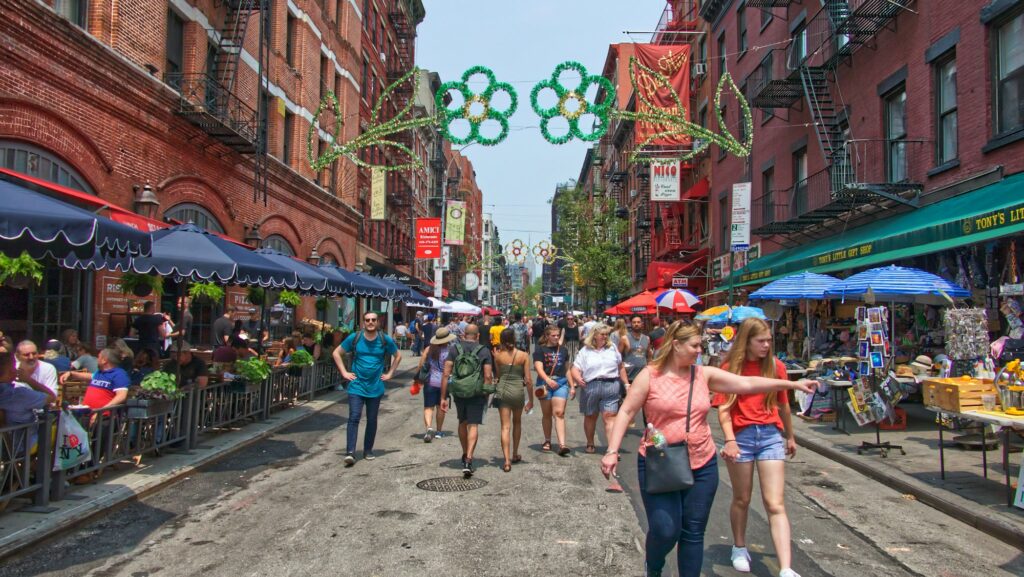 Outdoor tables and street lights on Mulberry Street in Little Italy, with the Empire State Building in the distance