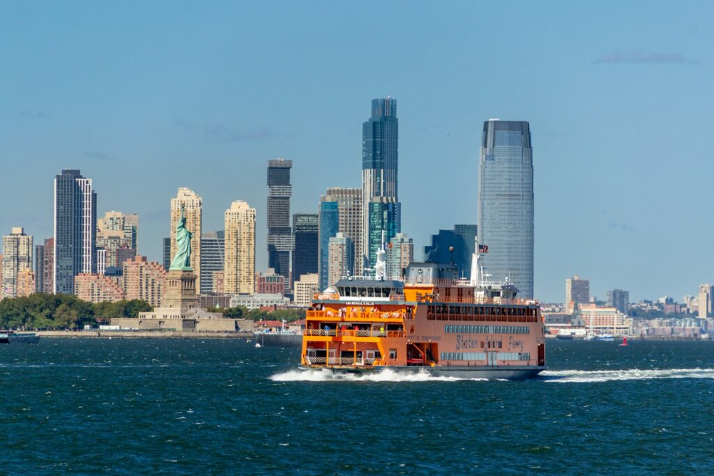The orange Staten Island Ferry crossing New York Harbor, with the Statue of Liberty behind it