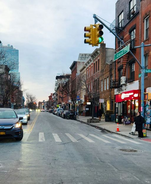 A busy street in Williamsburg, Brooklyn, lined with brownstone buildings and local shops