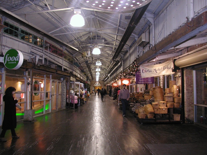 Shoppers walking along the brick-floored main hall of Chelsea Market