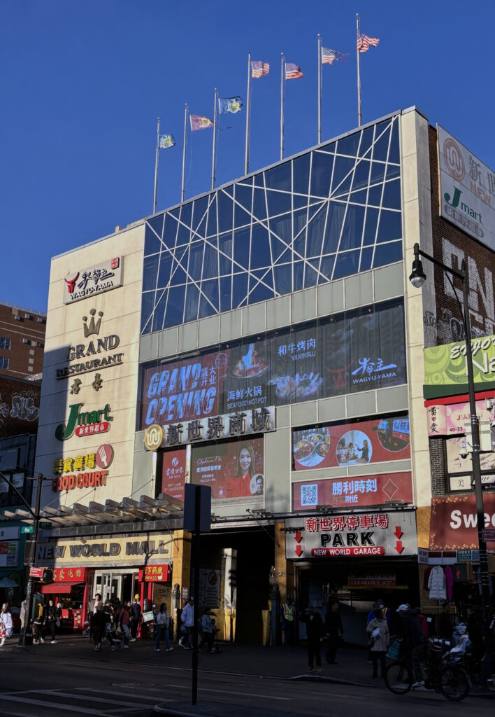 The New World Mall building on Main Street in Flushing, with its Food Court sign and flags on the roof