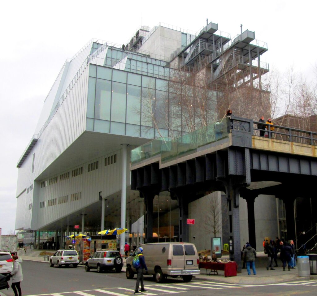 The Whitney Museum of American Art’s steel-and-glass building on Gansevoort Street, with people looking out from the end of the High Line beside it