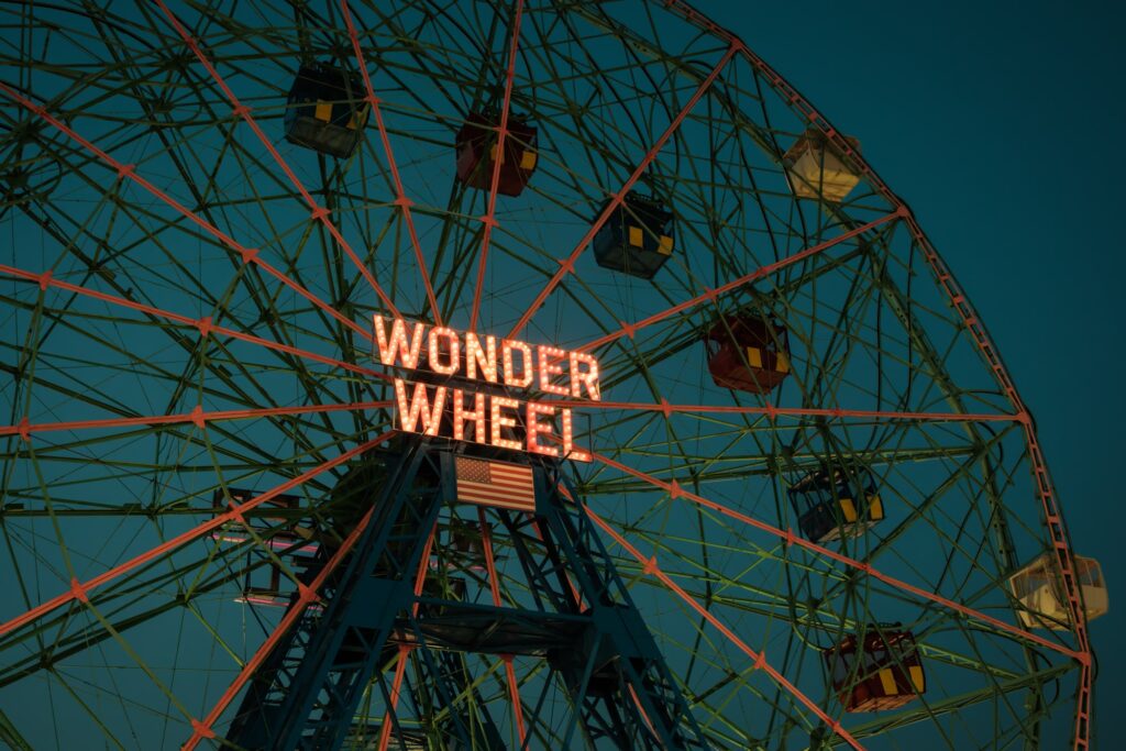 The lit Wonder Wheel sign at Coney Island against an evening sky