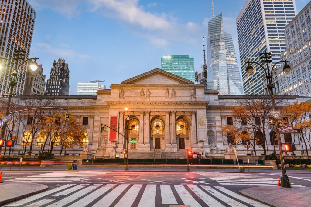 The marble Fifth Avenue facade of the New York Public Library at dusk, with its stone lions by the steps