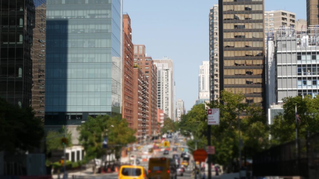A long Upper East Side avenue lined with apartment towers, trees and yellow taxis