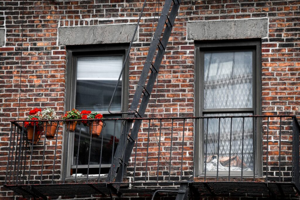 Red brick building with a black iron fire escape and potted flowers in New York