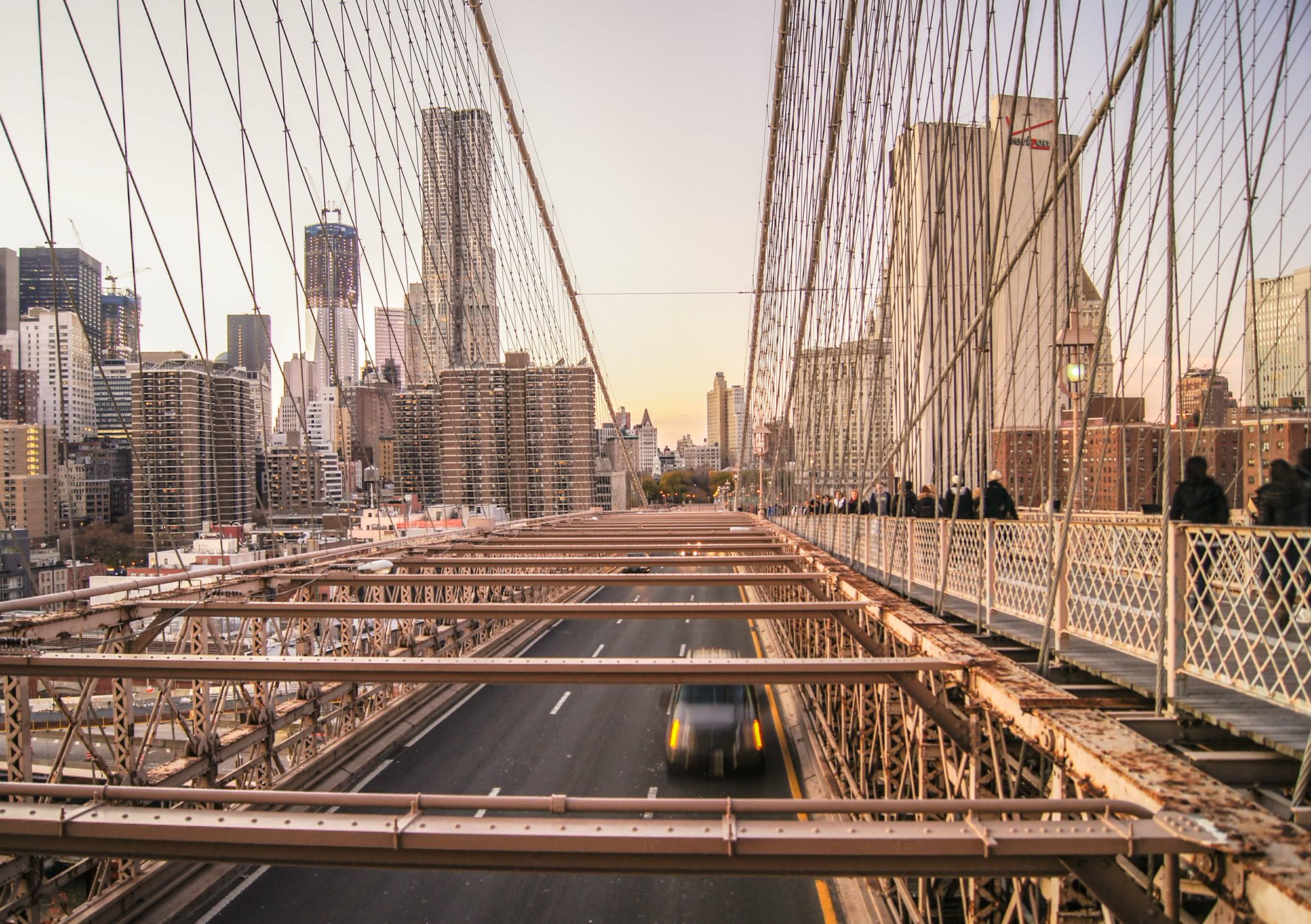 Brooklyn Bridge at sunset with the Lower Manhattan skyline beyond the cables