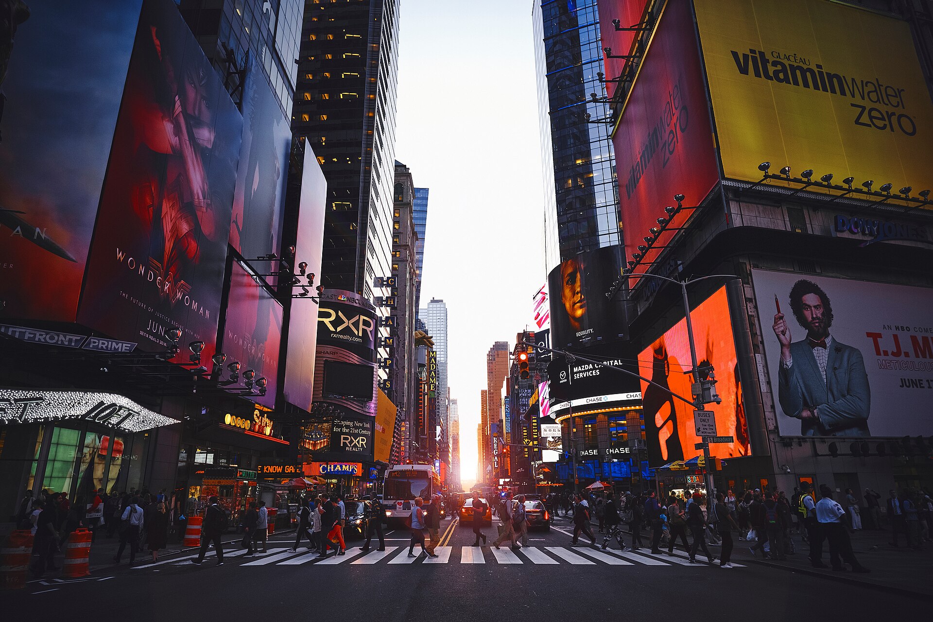 Sunset over Times Square, New York City, with warm golden light reflecting off buildings and billboards