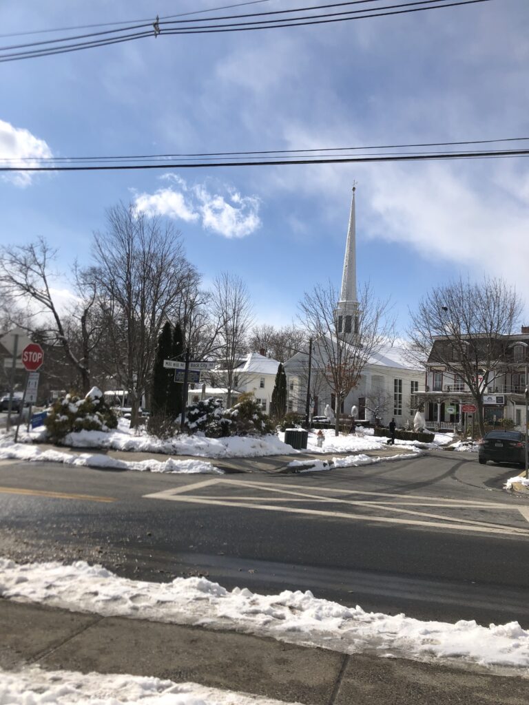 The white spire of the Woodstock Dutch Reformed Church above the village green on a snowy winter day