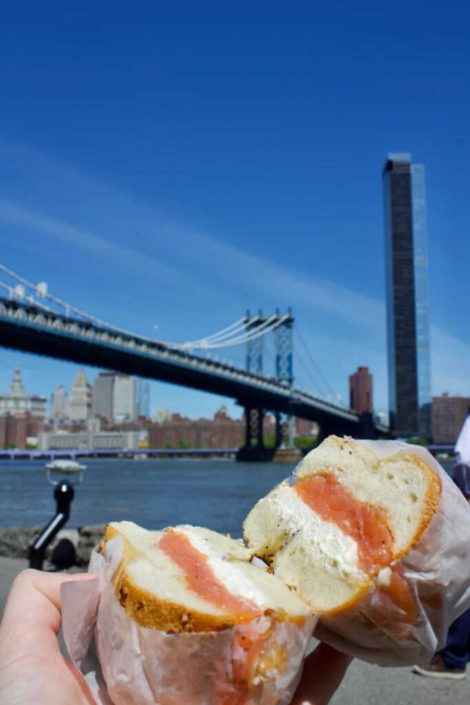Hand holding a split bagel with cream cheese and lox