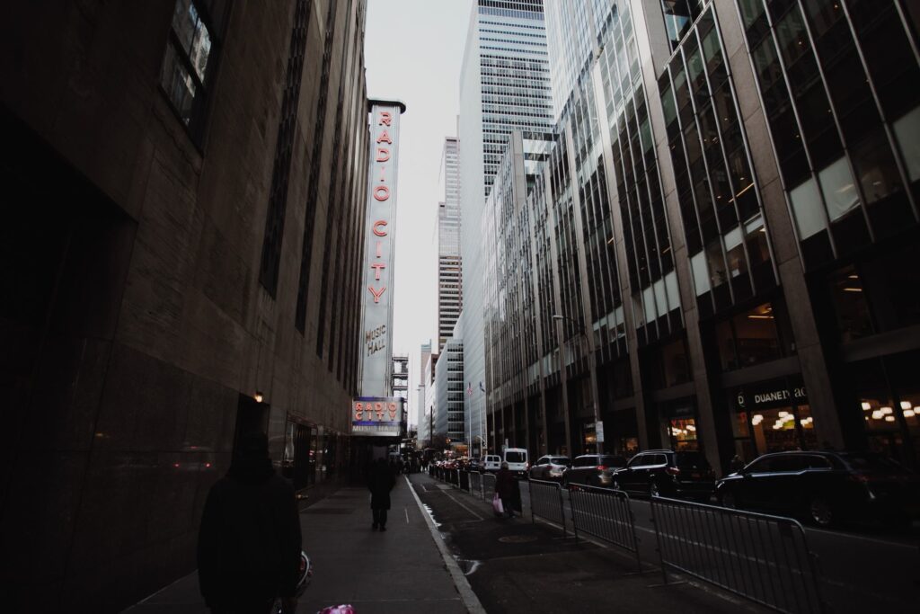 The vertical Radio City Music Hall sign on a Midtown street lined with office towers