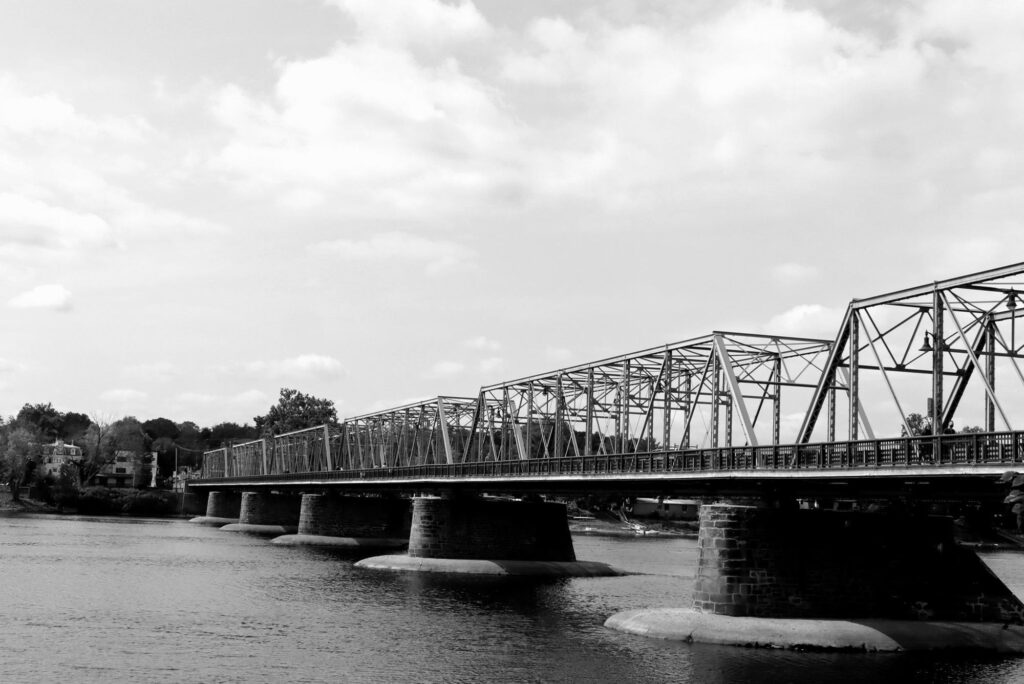 Black-and-white view of the steel truss bridge on stone piers across the Delaware River at New Hope