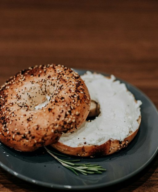 A classic New York everything bagel with cream cheese on a dark plate — one of the city's most iconic foods