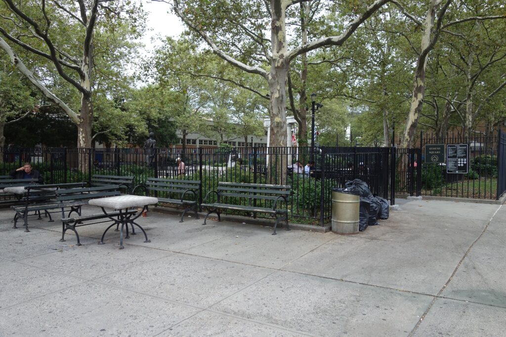 Benches and plane trees at the entrance to Athens Square Park on 30th Avenue in Astoria