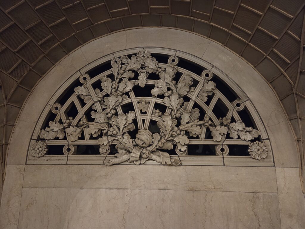 A carved oak-leaf grille set in a marble arch under the tiled vault of the Whispering Gallery at Grand Central Terminal