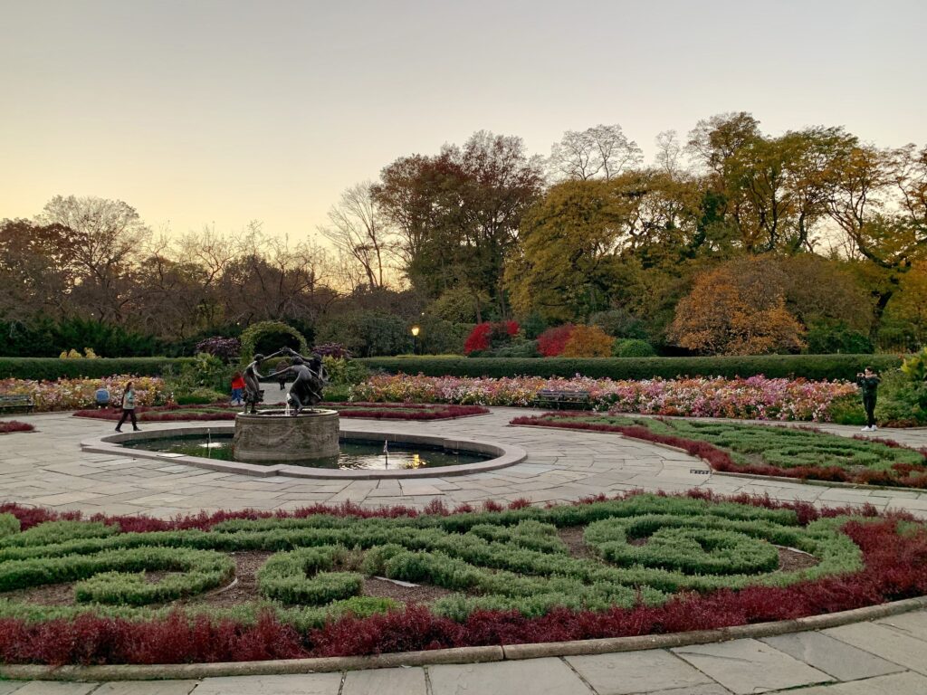 The Untermyer Fountain of three dancing maidens in the French garden of the Conservatory Garden, with fall flower beds and benches
