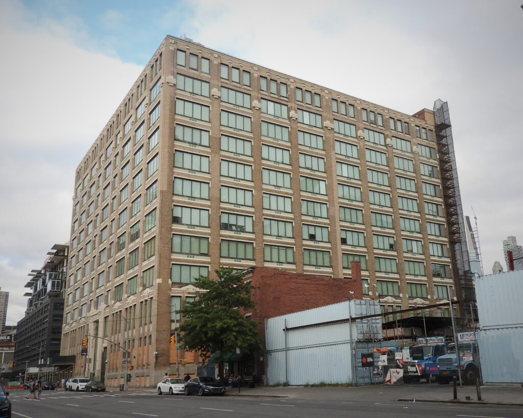 The tan-brick former printing plant at 11th Avenue and 48th Street that houses the Ink 48 hotel, seen from the street on a cloudy day